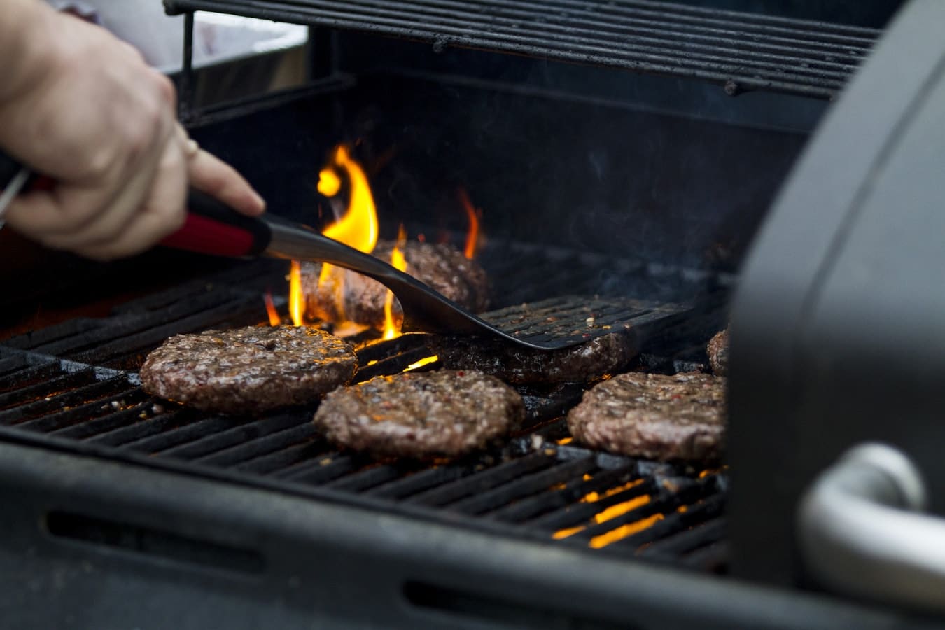 A man grilling burgers on a grille outside
